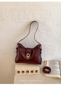 Detail of dark burgundy retro underarm bag with gold lock and detachable shoulder strap