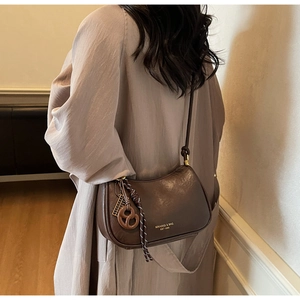 Close-up of matte dark brown leather crossbody bag featuring unique woven rope charms