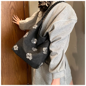 Detail view of dark grey canvas tote with shiny silver flower sequins and braided strap