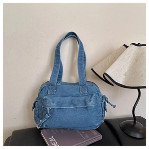 Close-up of washed blue denim shoulder bag featuring multiple pockets and metal zippers