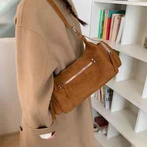 Detail of brown suede shoulder bag with silver zipper and rivets on model