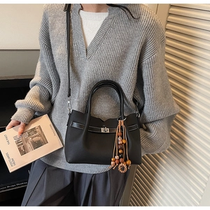 Detail of black faux leather tote bag with silver twist lock and wooden bead accessory