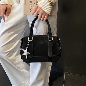 Détail du sac Boston noir en daim avec doubles poignées et pendentif étoile argenté