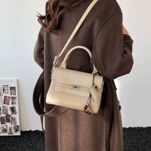 Detail showing the mixed beige leather and straw textures with silver twist lock and tassel