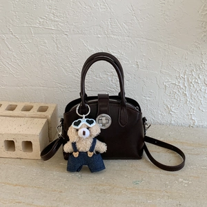 Detailed view of chocolate brown crossbody bag with silver lock and teddy bear charm