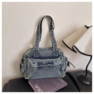 Detailed view of a retro blue washed denim shoulder bag with front zipper and side pockets