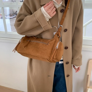 Detailed macro shot of the brown matte suede texture and zipper pockets on the shoulder bag