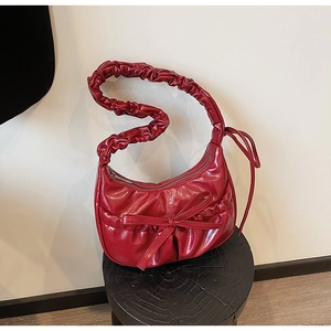 Détail du sac hobo rouge en similicuir brillant avec une anse au design plissé