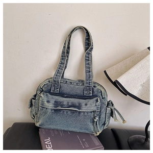 Close-up of retro washed blue denim shoulder bag featuring utility zipper pockets and knot details