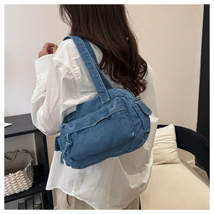 Side view of multi-pocket denim shoulder bag worn by model in a cozy interior