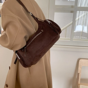Detailed view of model wearing a vintage brown suede cylinder bag with silver zipper detail