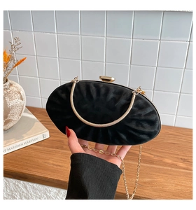 Detail of black pleated evening bag with gold snake handle and metallic chain strap