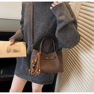 Detail of vintage brown tote bag with metal twist lock and ethnic tassel pendant