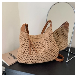 Détail de la texture tissée et de la bandoulière en cuir brun d'un sac cabas beige