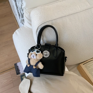 Detail of black leather handbag with silver twist lock and cute bear plush charm accessory