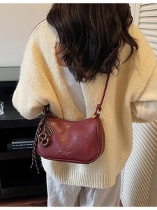 Minimalist burgundy half-moon crossbody bag with decorative scarf shown on a model