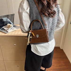 Detailed view of a brown crossbody bag with silver buckle and bohemian beaded tassel