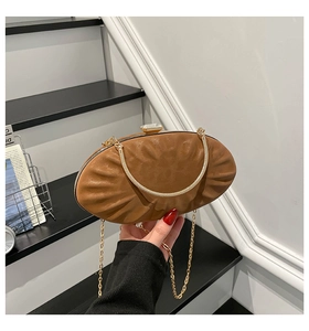 Close-up of brown pleated oval clutch with crystal buckle and golden chain strap