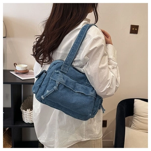 Detail view of vintage blue denim shoulder bag with multiple utility pockets and fringes