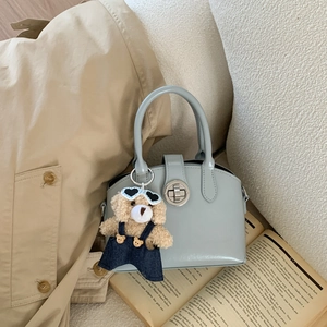 Detailed view of light blue handbag featuring a cute teddy bear charm and metal buckle