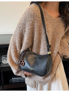 Minimalist black leather crossbody bag with knot strap and gold accents for women