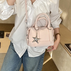 Détail du sac Boston en cuir grainé rose avec pendentif étoile et bandoulière longue