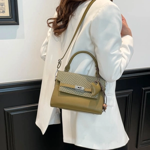 Detail of olive green crossbody bag with houndstooth flap and heart pendant decoration