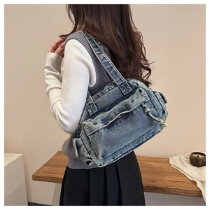 Detail of vintage denim tote bag showing side pockets and thick shoulder strap on model