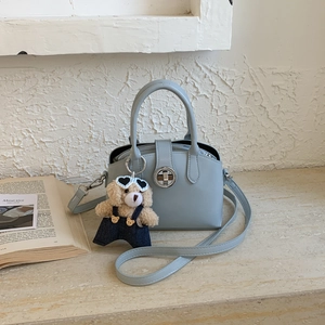 Detail of light blue PU leather handbag featuring silver twist lock and cute bear charm
