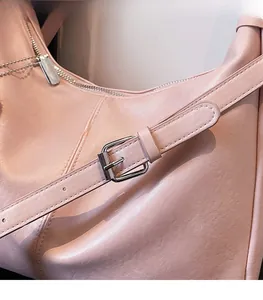 Detail of adjustable shoulder strap with silver buckle on pink slouchy hobo bag