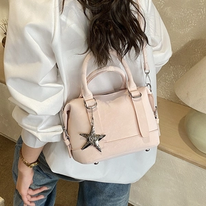 Gros plan sur le sac Boston rose avec pendentif étoile argenté et cuir synthétique