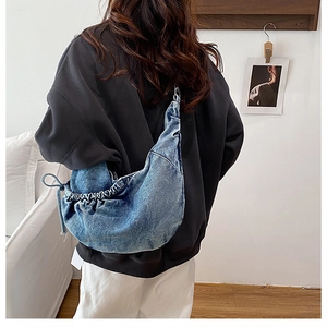 Detail view of large denim hobo crossbody bag with side drawstring and soft fabric texture