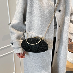 Detail of elegant black velvet evening bag with gold chain and handle on gray wool coat