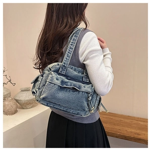 Lifestyle shot of vintage washed denim shoulder bag with functional zipper pocket