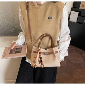 Detail of retro tote bag with wooden bead tassels and leather trim on model outfit