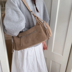 Detail of a brown suede crossbody bag showing textured fabric and silver metallic zippers