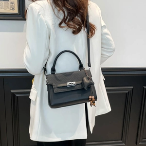 Detail of black crossbody bag with V-quilted texture and heart tassel charm