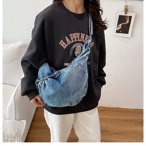 Lifestyle shot of large crescent denim crossbody bag with pleated edges and middle-wash finish