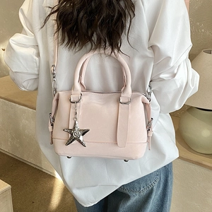 Détail d'un mini sac boston rose clair avec breloque étoile et bandoulière réglable