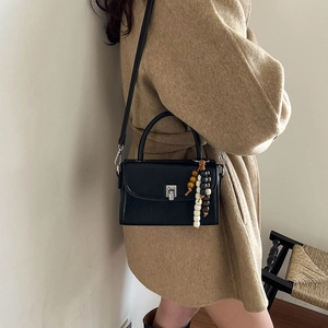Classic black leather crossbody handbag with silver clasp and wooden bead charm accessory