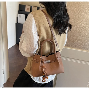 Detailed close-up of brown vintage tote bag featuring a metal twist lock and bead tassel