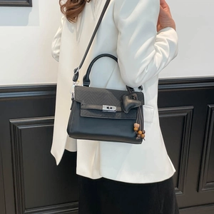 Detail of black crossbody bag with silver twist lock and heart pendant charm