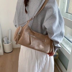 Khaki suede cylinder shoulder bag with silver zippers shown on a person for lifestyle