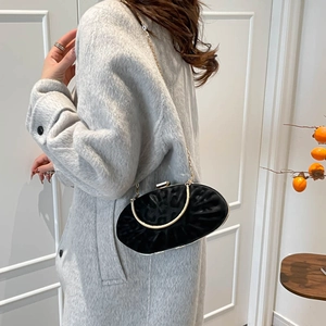 Detail of black velvet evening bag with gold handle and chain on elegant model