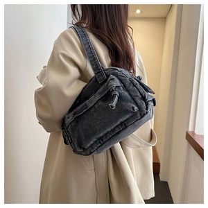 Detail showing the vintage washed black denim texture and multi-pocket design on the bag