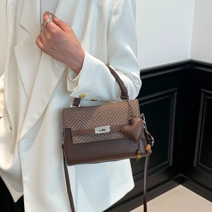 Close-up of brown houndstooth crossbody bag with silver turn-lock and leather heart charm