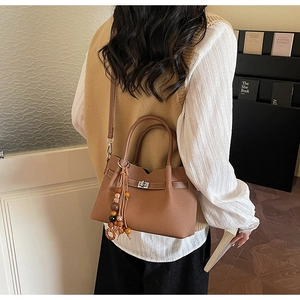 Detailed shot of brown textured leather tote bag with wooden bead fringe and metal clasp