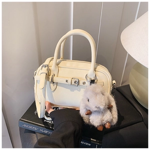 Detail of off-white leather handbag with buckle design and plush rabbit charm