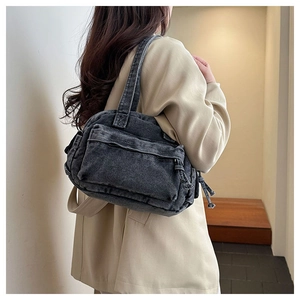 Detail of vintage black denim shoulder bag featuring multi-zipper pockets and washed texture