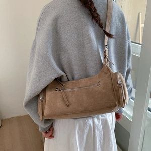 Detail of a brown suede bowling-style crossbody bag showing the premium textured material